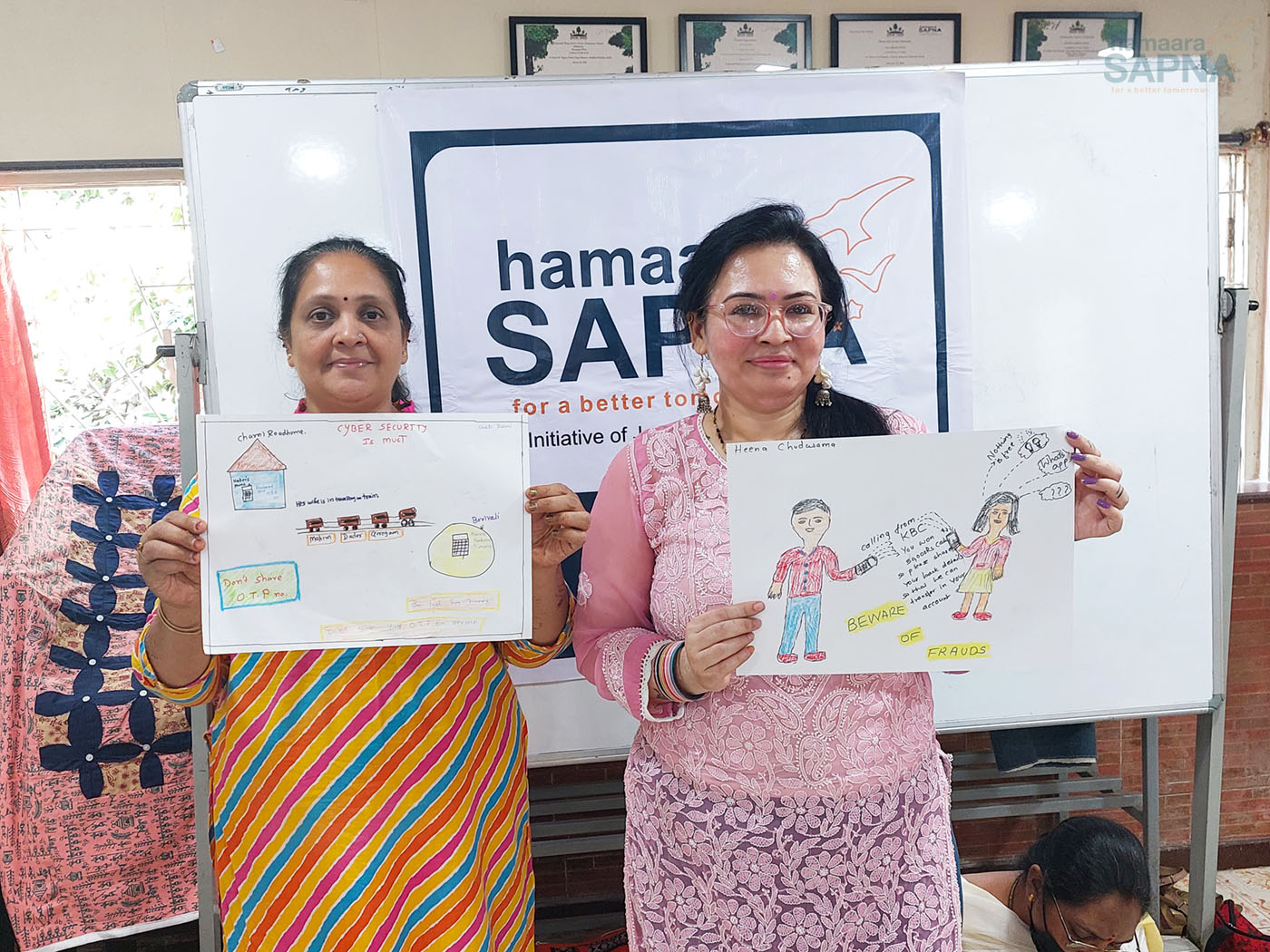 Two beneficiaries holding up the creative posters they made to spread awareness about cyber crime through the project 